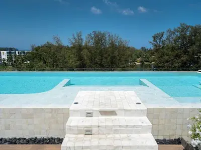 a large swimming pool with blue water and trees at 2 спальни Апартаменты на Бангтао 600 метров от моря in Bang Tao Beach