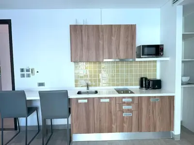 a kitchen with wooden cabinets and a sink and a microwave at Studio with pool access - Twin Sands by Lofty in Patong Beach