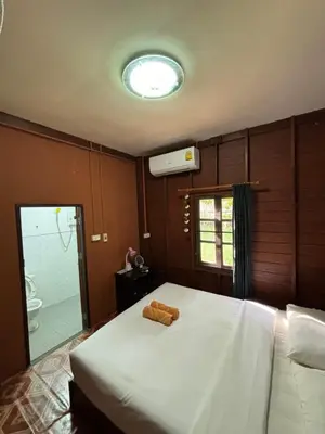 a bedroom with a large white bed and a window at Baan Ja Da in Ban Nai Khlong