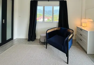 a room with a chair and a dresser and a window at Gloria’s Home in Kamala Beach