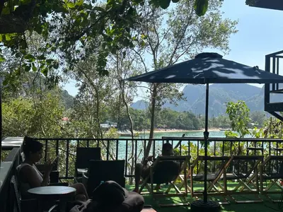 a group of people sitting in chairs under an umbrella at Sweed Dee Seaview Hostel in Phi Phi Don