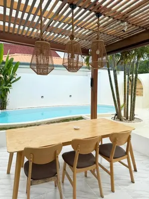 a dining room with a wooden table and chairs at 2BR Pool Villa&Garden - Bali style by La Perla Phuket Rawai in Ban Saiyuan (1)
