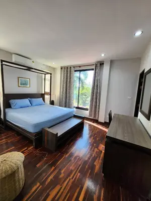 a bedroom with a bed and a large window at KRAAM VILLAS in Thalang