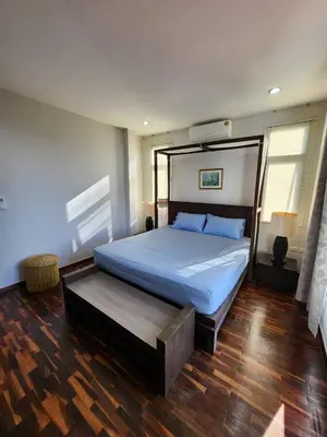 a bedroom with a large bed and a wooden floor at KRAAM VILLAS in Thalang