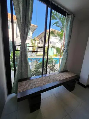 a window with a bench in a room with a view of a pool at KRAAM VILLAS in Thalang