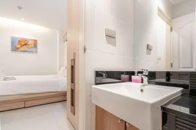 a white bathroom with a sink and a bed at The Lago apartments 2bd in Phuket Town