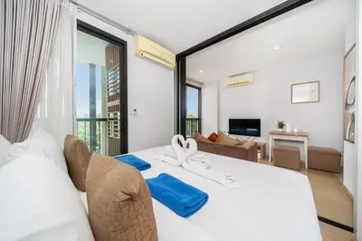 a bedroom with a white bed and a living room at Private apartment Zcape2 near Boat Avenue in Bang Tao Beach