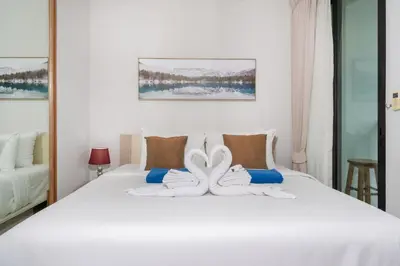 a bedroom with a white bed with towels on it at Private apartment Zcape2 near Boat Avenue in Bang Tao Beach
