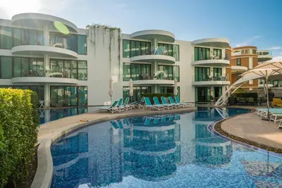 a swimming pool with chairs and a building at Private apartment at Twin Sands by Lofty in Patong Beach