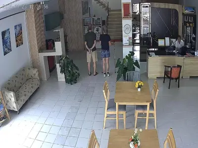 two men standing in a restaurant with tables and chairs at NAKA GUEST HOUSE in Ban Ko Kwang