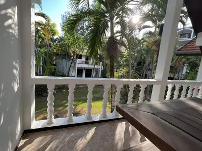 a porch with a white railing and palm trees at Charming Villa Suite with Balcony near Beach in Patong Beach