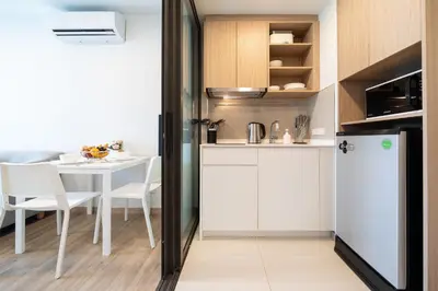 a kitchen with a table and a white refrigerator at Laguna BangTao Beach Skypark Apartment in Phuket Town
