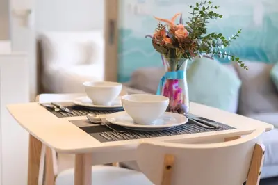 a table with two cups and a vase with flowers at Laguna BangTao Beach Skypark Apartment in Phuket Town