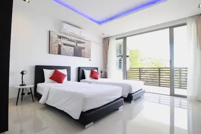 two beds in a bedroom with white walls and red pillows at Luxury Rooftop Penthouse in Kamala Beach