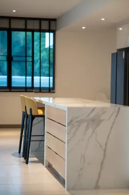 a kitchen with a marble counter top and chairs at 5 Bdr 18 meter Pool villa in Laguna Phuket in Phuket Town