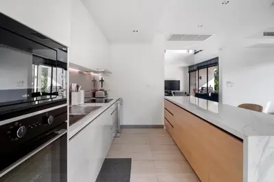 a kitchen with white walls and a long counter at 5 Bdr 18 meter Pool villa in Laguna Phuket in Phuket Town