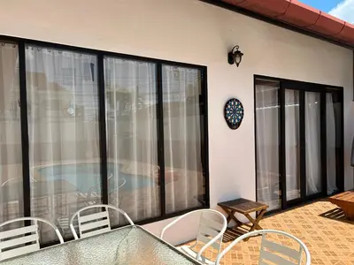 a balcony with a table and chairs and a pool at Villa KEWALYN in Chalong