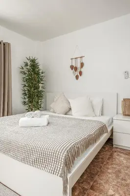 a white bedroom with a white bed with a plant at Nai Harn beach Villa 2 bdr in Rawai Beach