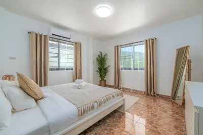 a bedroom with a white bed and two windows at Nai Harn beach Villa 2 bdr in Rawai Beach