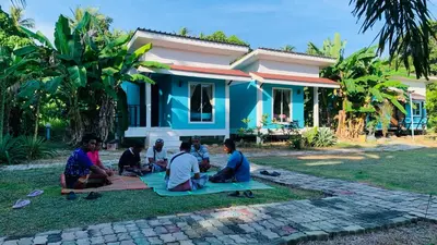 a group of people sitting on the grass in front of a house at Yada Resort Koh Yao Noi in Ko Yao Noi
