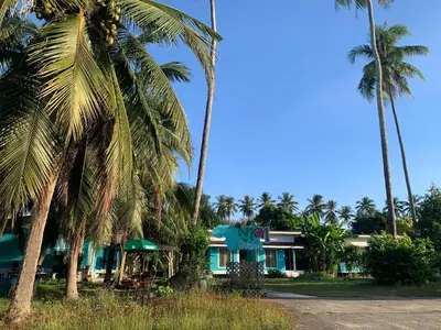 a blue house with palm trees in front of it at Yada Resort Koh Yao Noi in Ko Yao Noi