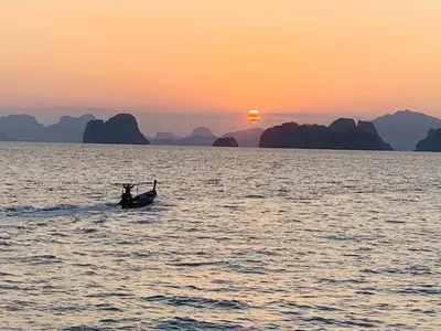 a person in a boat in the water at sunset at Yada Resort Koh Yao Noi in Ko Yao Noi
