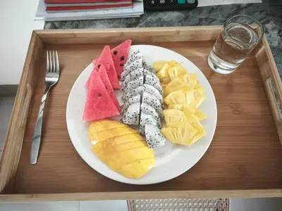 a white plate with fruit on a wooden tray at The Secret Garden Koh Yao Yai in Ko Yao Yai