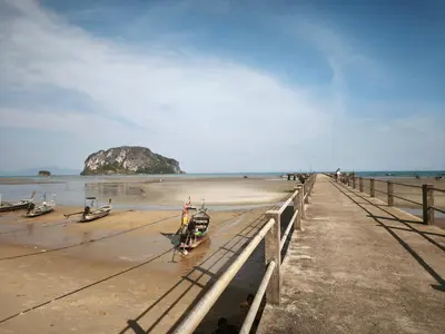 a beach with boats on the sand and a pier at The Secret Garden Koh Yao Yai in Ko Yao Yai