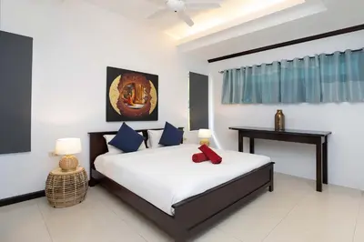 a bedroom with a bed and a table in it at Tropical 3BR Pool Villa Prima, just 5min Drive to NaiHarn and Rawai Beach in Rawai Beach