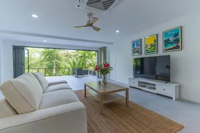 a living room with a white couch and a tv at Ray Ray Villa by G Estate Phuket in Kata Beach
