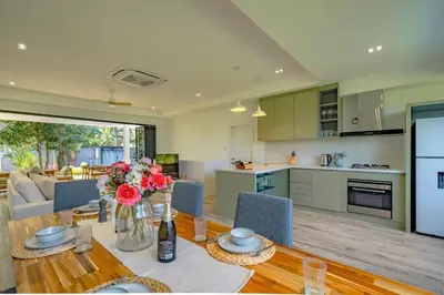 a kitchen and living room with a table with flowers at Ray Ray Villa by G Estate Phuket in Kata Beach