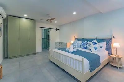 a bedroom with a large bed with blue and white pillows at Ray Ray Villa by G Estate Phuket in Kata Beach
