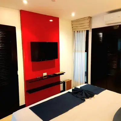a bedroom with a red wall with a tv on it at Dewa One bedroom suite in Nai Yang Beach
