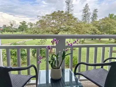 a table with a vase with flowers on a balcony at Stylish 1 Bedroom Apartment with Golf View, Steps from Bang Tao Beach, Allamanda Laguna in Bang Tao Beach