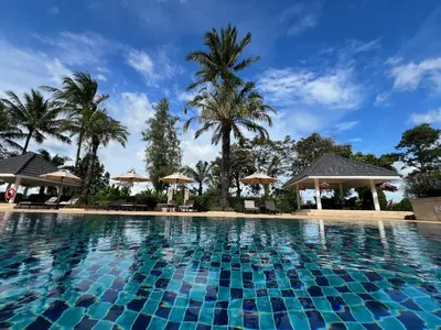 a pool at a resort with palm trees and umbrellas at Stylish 1 Bedroom Apartment with Golf View, Steps from Bang Tao Beach, Allamanda Laguna in Bang Tao Beach