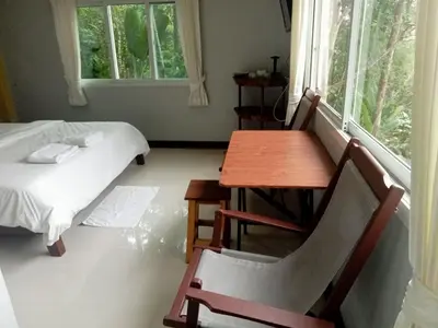 a room with a table and a bed and a table and chair at Kanda Hill Resort in Ban Na Sok