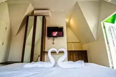 two white swans forming a heart on a bed at Kanda Hill Resort in Ban Na Sok