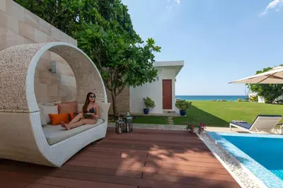 a woman sitting on a wicker chair next to a pool at Summer Estate Villa in Pilai Beach