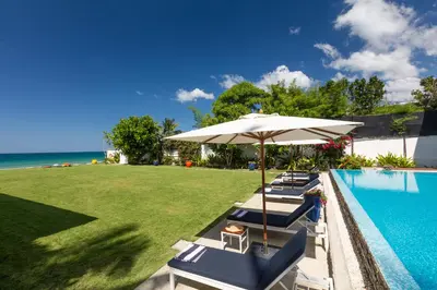 a group of chairs and an umbrella next to a swimming pool at Summer Estate Villa in Pilai Beach