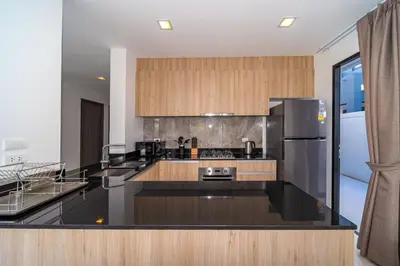 a kitchen with a black counter top and a refrigerator at 4bdr pool villa in Laguna Park 2 in Phuket Town