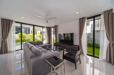a living room with a gray couch and a television at 4bdr pool villa in Laguna Park 2 in Phuket Town