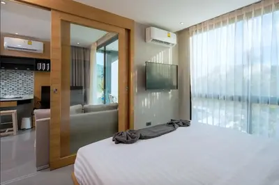 a bedroom with a bed and a tub and a television at Tropics Kamala Hill View Apartment CTG D709, near Beach and Fantasea in Kamala Beach