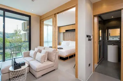 a bedroom with a bed and a couch and a chair at Tropics Kamala Hill View Apartment CTG D709, near Beach and Fantasea in Kamala Beach