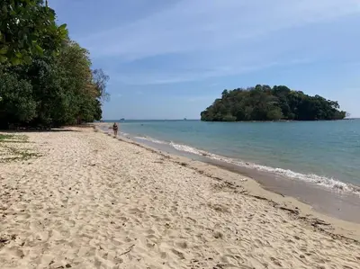 a beach with a person walking on the shore at Chez Wanida - apartment Krabi in Klong Muang Beach