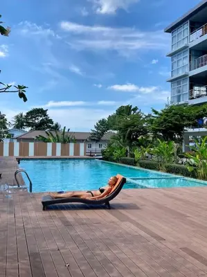 a woman laying in a hammock next to a swimming pool at Chez Wanida - apartment Krabi in Klong Muang Beach