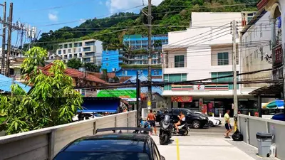 a busy city street with cars and people on a motorcycle at Hm House Patong in Patong Beach