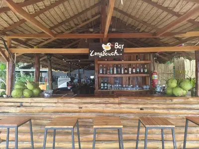 a bar with four chairs and a bar umbrella at Long Beach Club Krabi in Ban Nong Thale