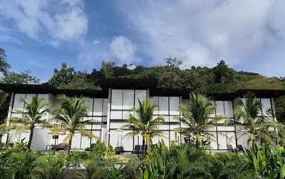 a building with palm trees in front of it at Sky Lofts Phuket in Nai Yang Beach