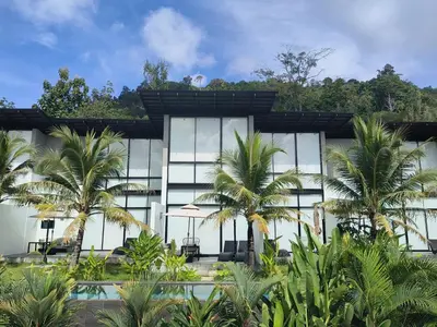 a building with palm trees in front of it at Sky Lofts Phuket in Nai Yang Beach