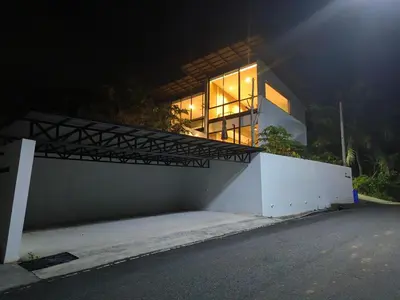 a house lit up at night with a balcony at Sky Lofts Phuket in Nai Yang Beach